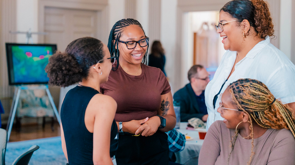 Students at UNCG's summer research celebration in August 2024 at the Alumni House laughing and talking